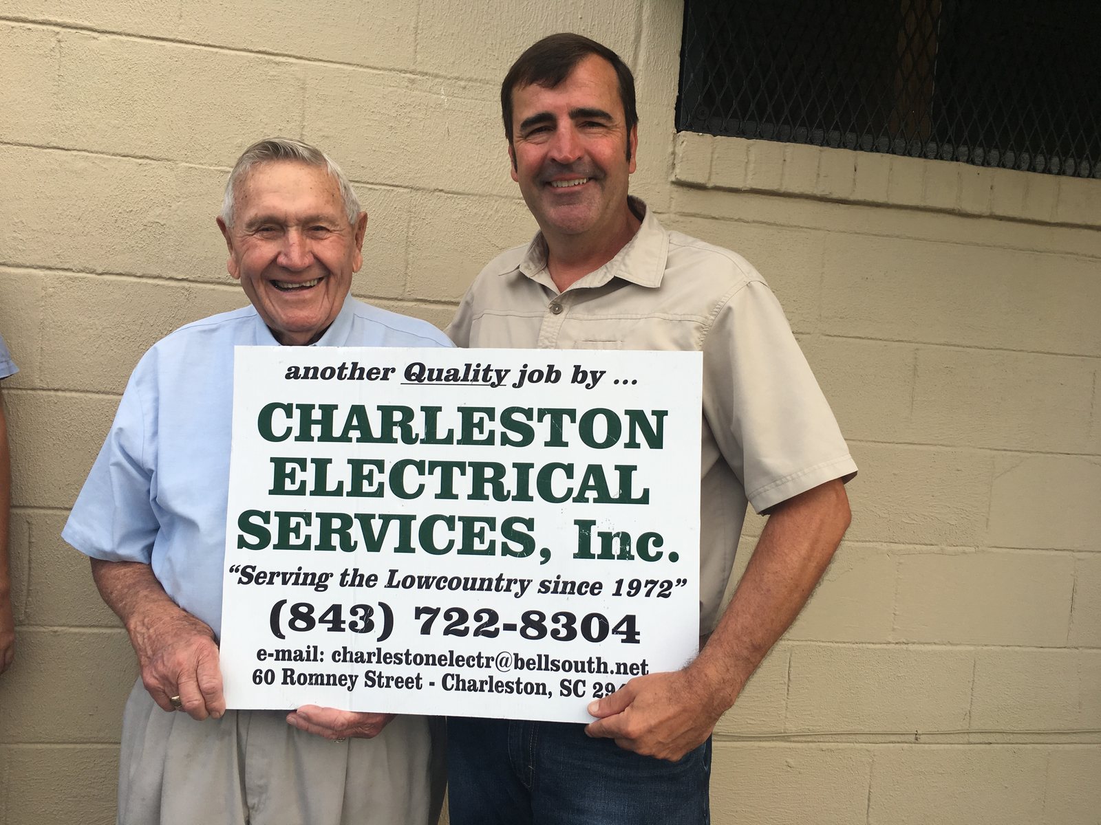 Founder George Kornahrens and CEO Johnny Oakley holding a Charleston Electrical Services sign